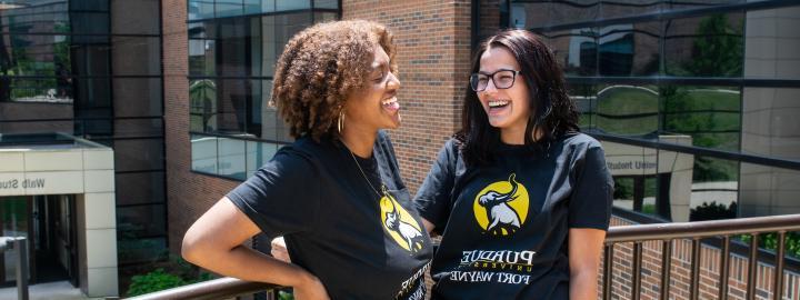 Two transfer students stand outside wearing PFW Transfer shirts.