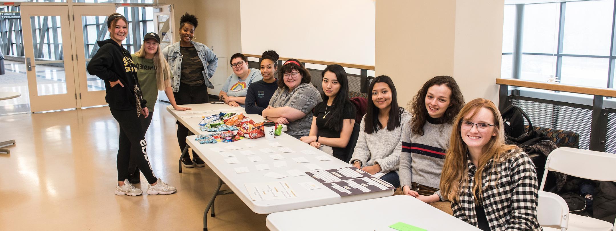 Students at a display table for a WOS event.