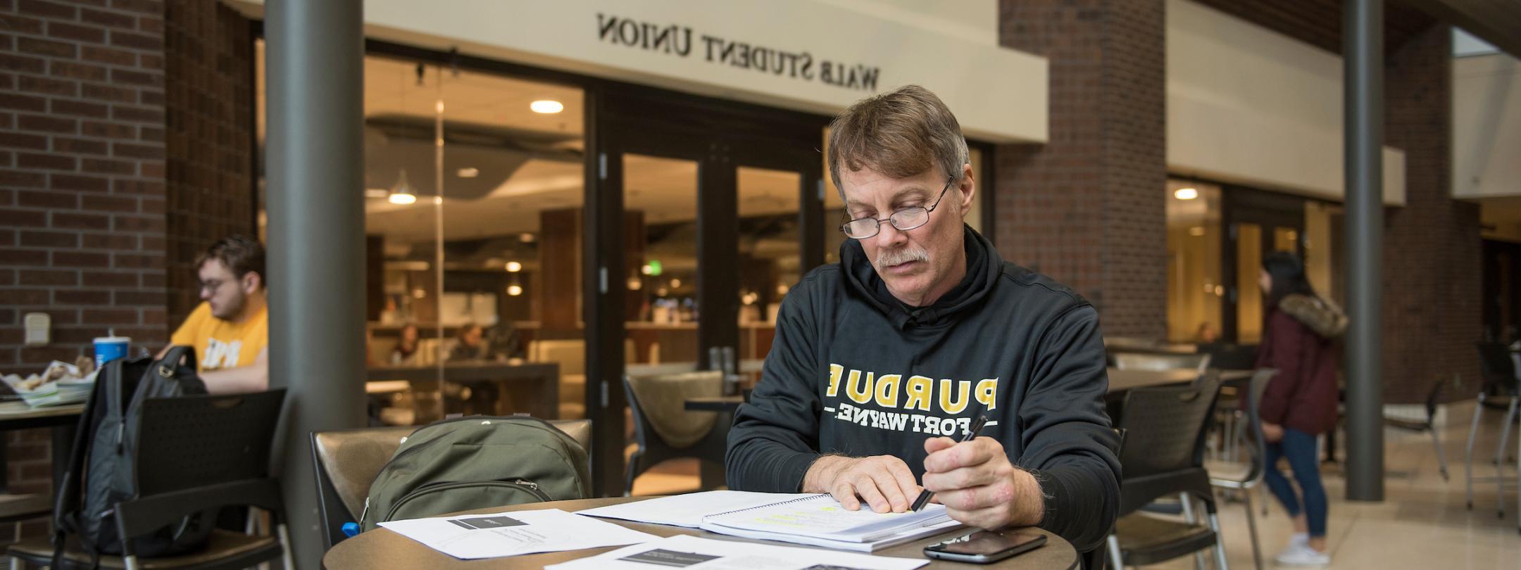 Adult student studying at a table in Wall.