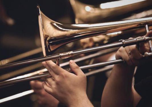 A close up of a hand playing a trombone.